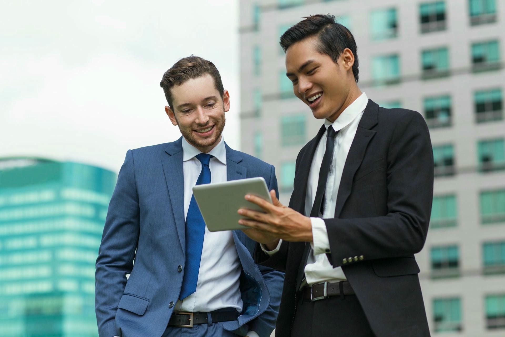 closeup smiling coworkers using tablet outdoors scaled